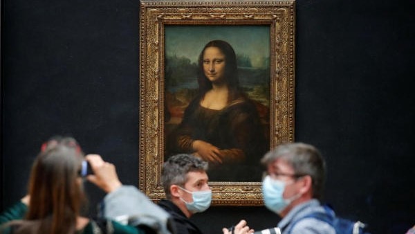 Media people, wearing protective face masks, stand in front of the painting "Mona Lisa" (La Joconde) by Leonardo Da Vinci at the Louvre museum in Paris.