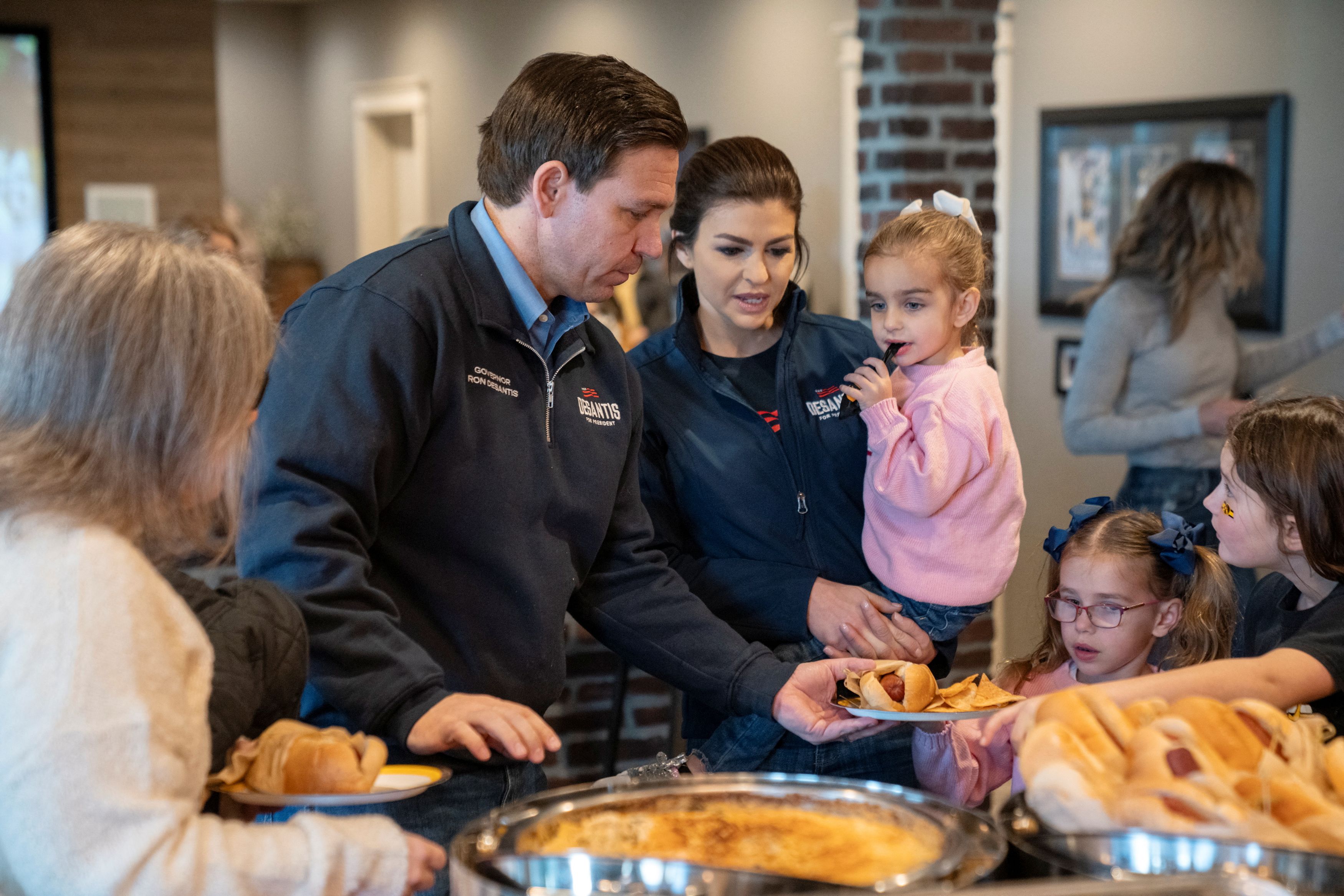 Republican presidential candidate Florida Governor Ron DeSantis hands a plate of food to his daughter Madison at a Citrus Bowl watch party at a private residence in Ankeny, Iowa, U.S., January 1, 2024.