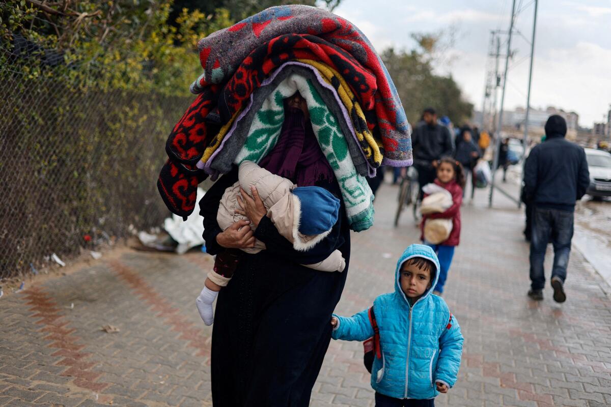 A woman holds a baby as Palestinians fleeing Khan Younis, due to the Israeli ground operation, move towards Rafah, amid the ongoing conflict between Israel and the Palestinian Islamist group Hamas, in the southern Gaza Strip, January 29, 2024.