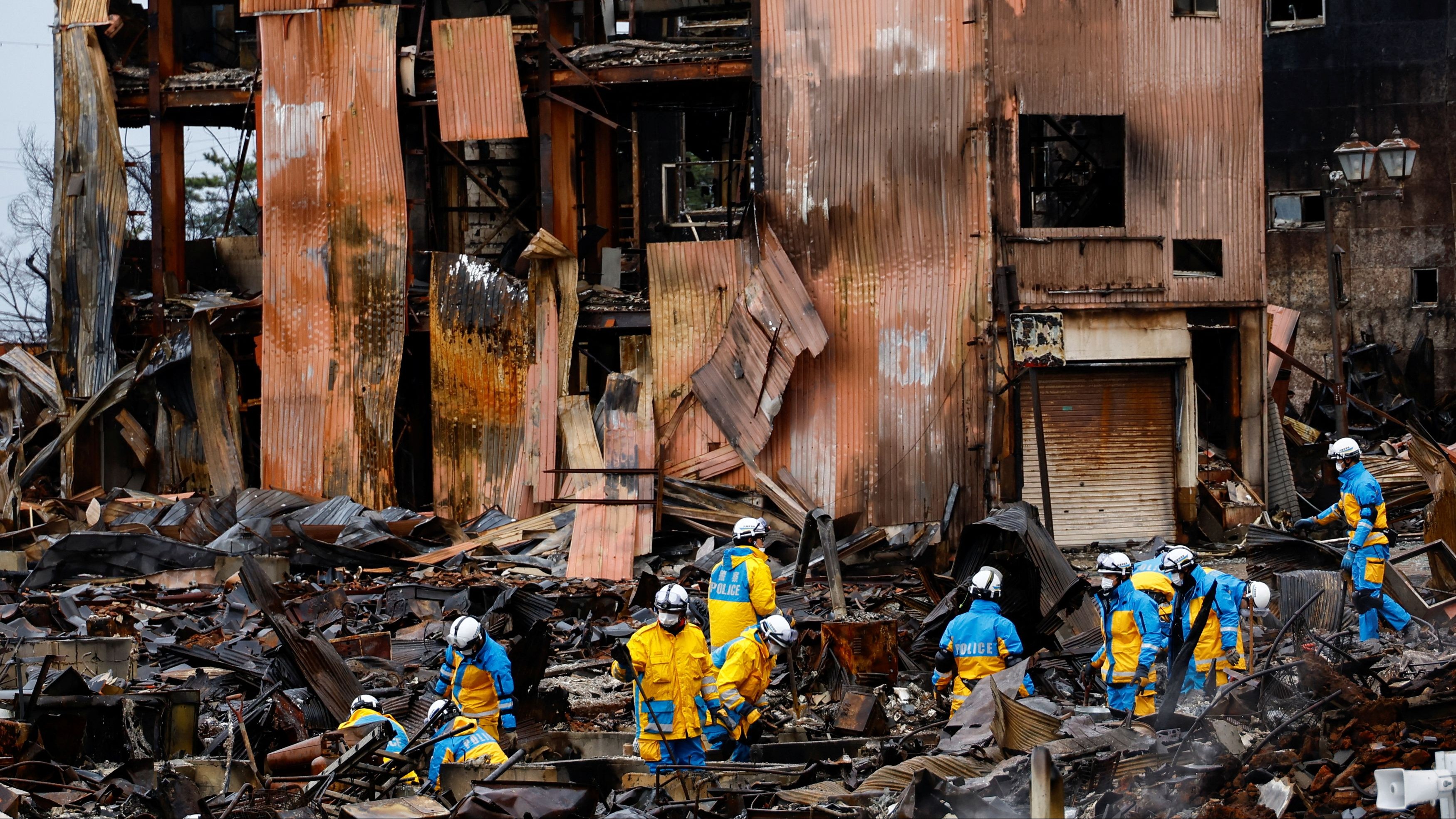 Policemen search for victims in Asaichi-dori street, which burned down due to a fire following an earthquake in Wajima, Ishikawa Prefecture, Japan, January 7, 2024.