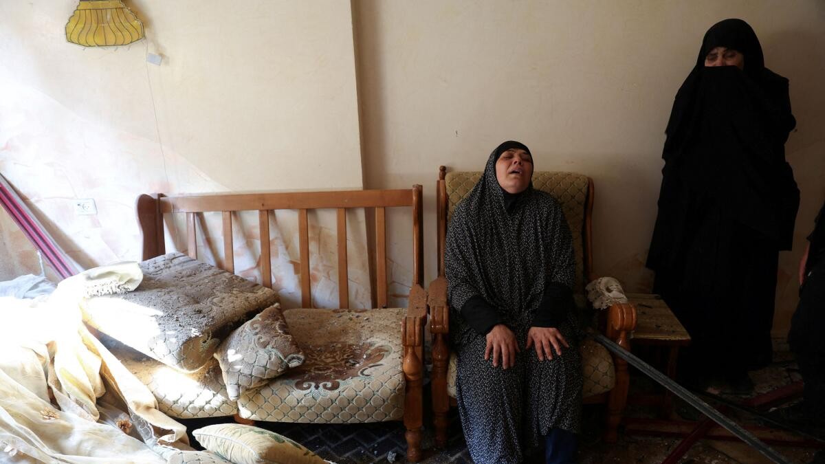 Palestinians inspect the site of an Israeli strike on a house, in Rafah.