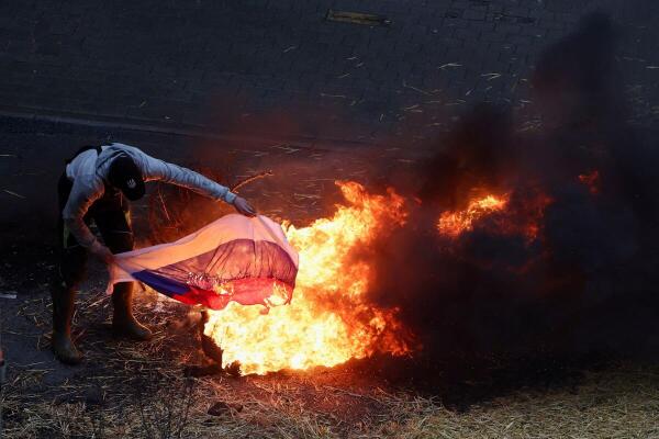 A farmer burns a Russian flag during a protest of European farmers over price pressures, taxes and green regulation, on the day of an EU Agriculture Ministers meeting in Brussels, Belgium February 26, 2024. 