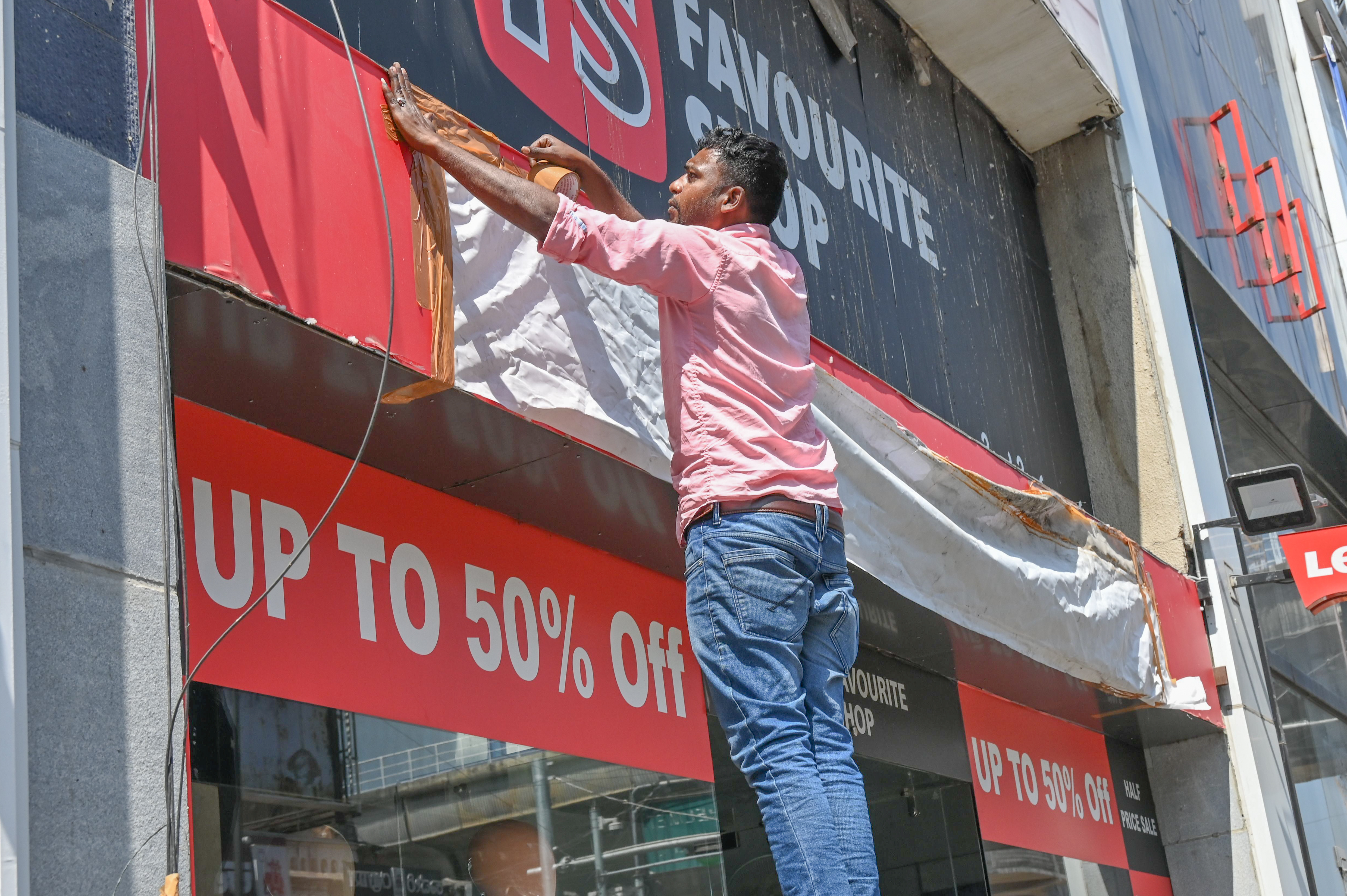 BBMP officials instruct shop owners at Brigade Road to cover the signboards. 