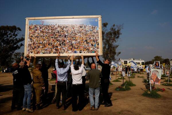 People help to raise a collage by artist Amir Chodorov depicting the faces of the Nova party victims, amid the ongoing conflict between Israel and the Palestinian Islamist group Hamas, in Reim, southern Israel, February 25, 2024.