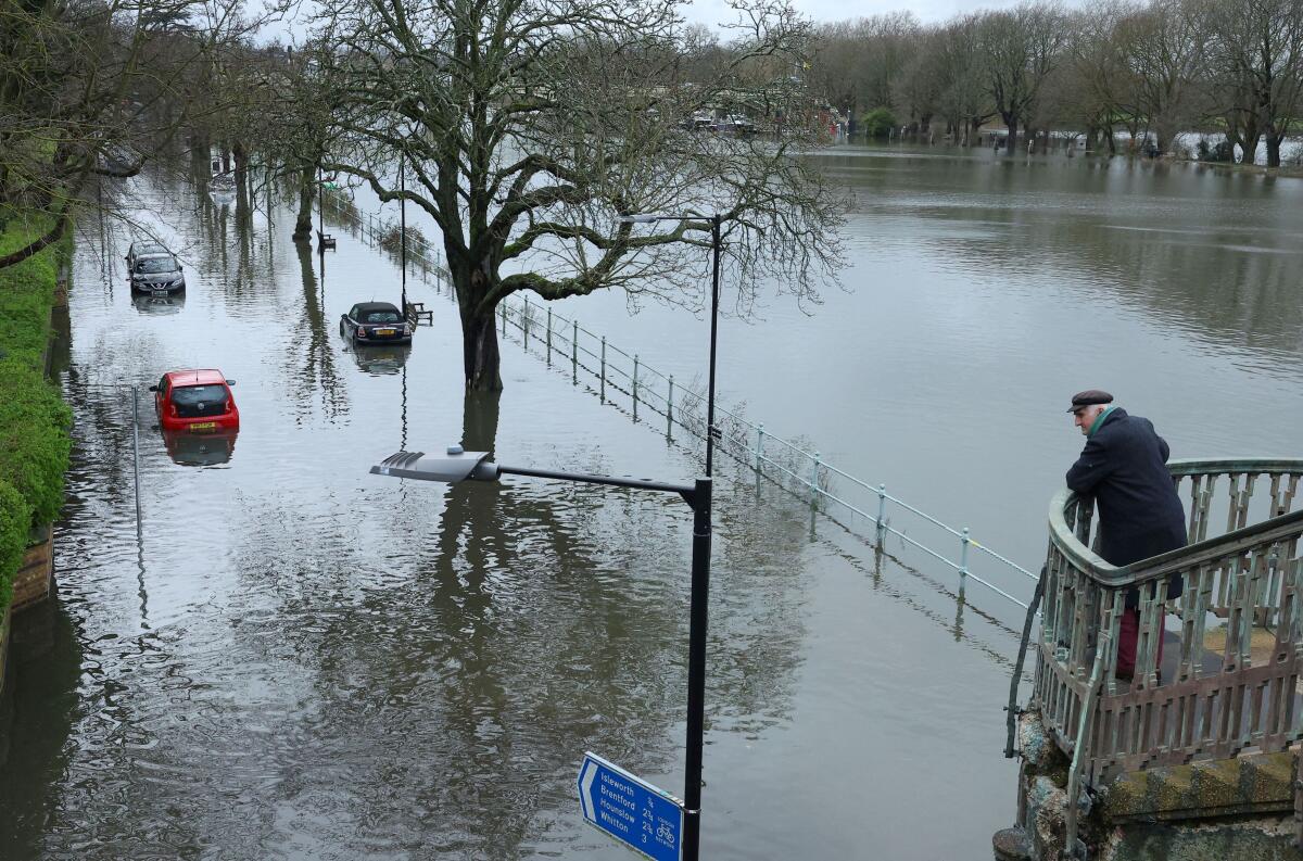 A man looks towards partially submerged cars as the River Thames bursts its banks at high tide, in Richmond in London, Britain, March 12, 2024.