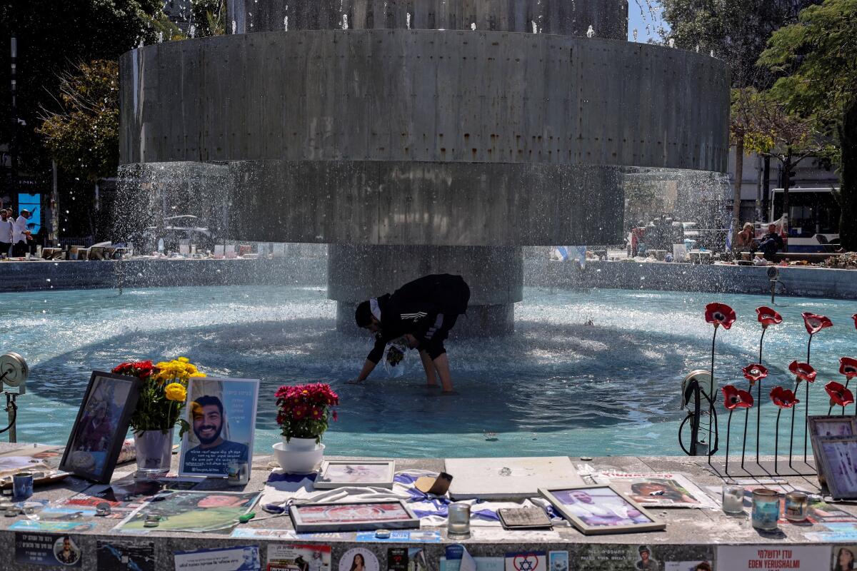 A man clears a water fountain adorned with messages and pictures of Israeli hostages held in the Gaza Strip, amid the ongoing conflict between Israel and the Palestinian Islamist group Hamas, in Tel Aviv, Israel, March 12, 2024.