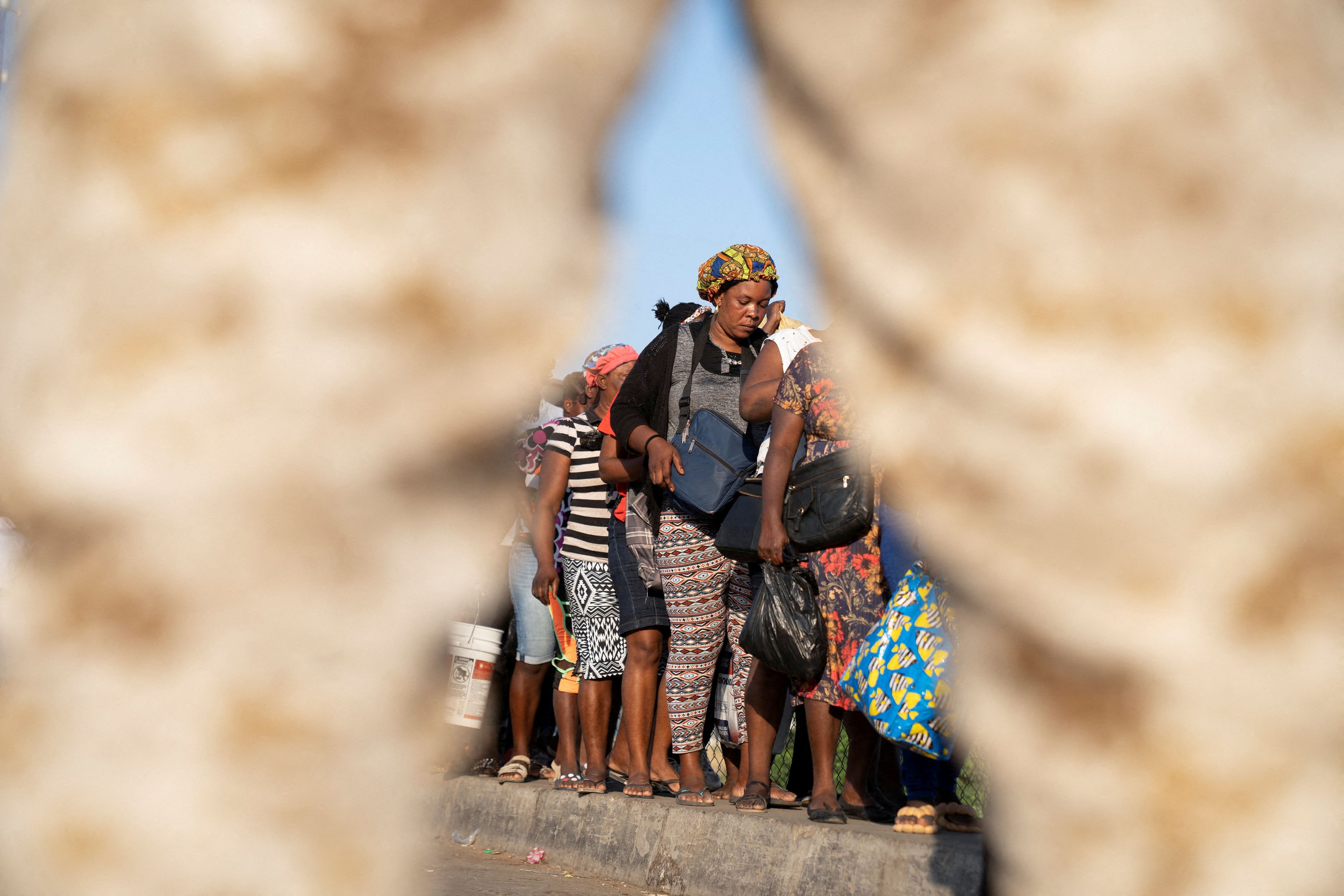 A Dominican Republic soldier keeps watch as Haitians queue while crossing the border after they were allowed into a market for needed essentials and trade, as gang violence continues in the aftermath of the resignation of Haiti's Prime Minister Ariel Henry, at a farmer's market in the border town of Dajabon, Dominican Republic, March 18, 2024. 