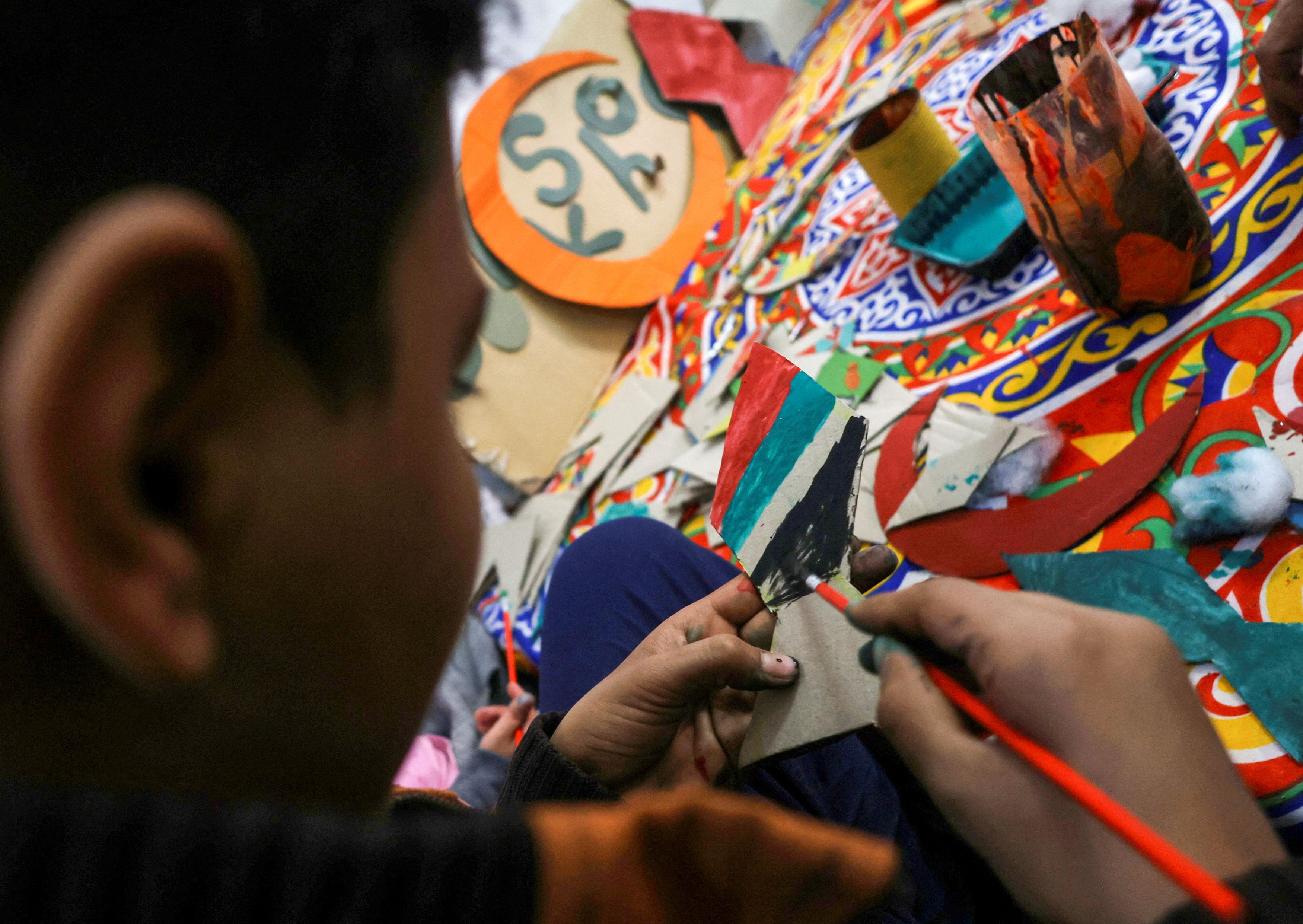 An Egyptian boy paints a piece of cardboard with the colours of the Palestinian flag at the art studio of Imad Hassan Anwar, founder of the Adam Association for Human Development and Zebala Store project, as children learn to make Ramadan decorations like traditional lanterns and crescents from recycled waste, in an initiative to engrave values and to entrench the Palestinian cause in their minds, in Giza, Egypt, March 15, 2024. 