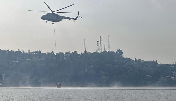 An Mi-17 V5 helicopter of the Indian Air Force conducts a 'Bambi Bucket Operation' to control the fire that broke out in the forests of Kumaon division, in Nainital district of Uttarakhand.