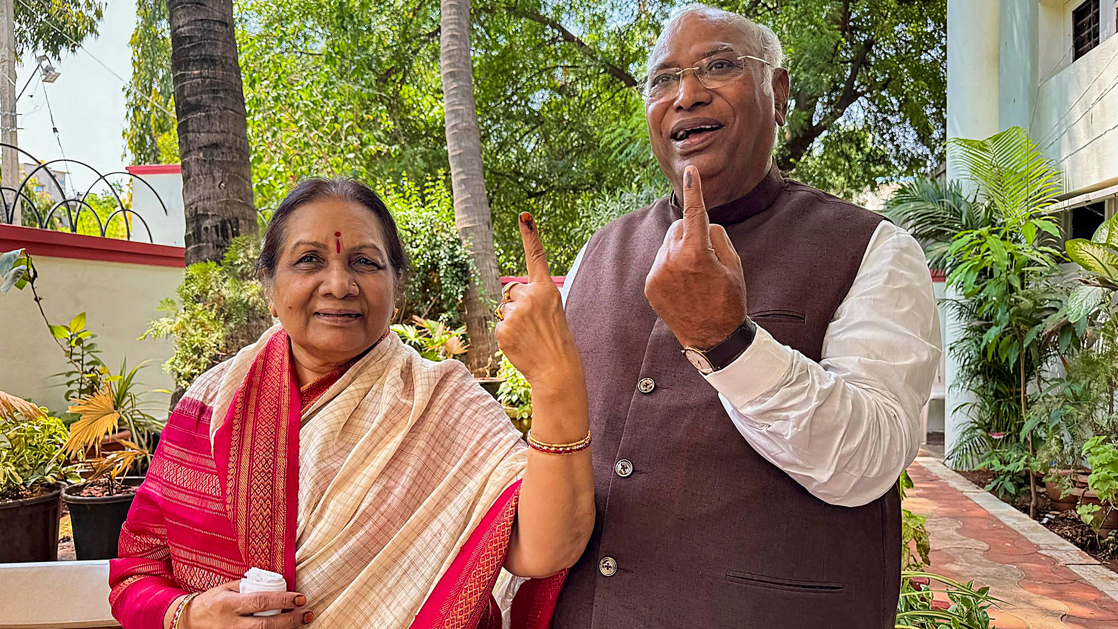 Congress President Mallikarjun Kharge with his wife Radhabai Kharge shows his ink-marked finger after voting during the third phase of Lok Sabha elections, in Kalaburagi.