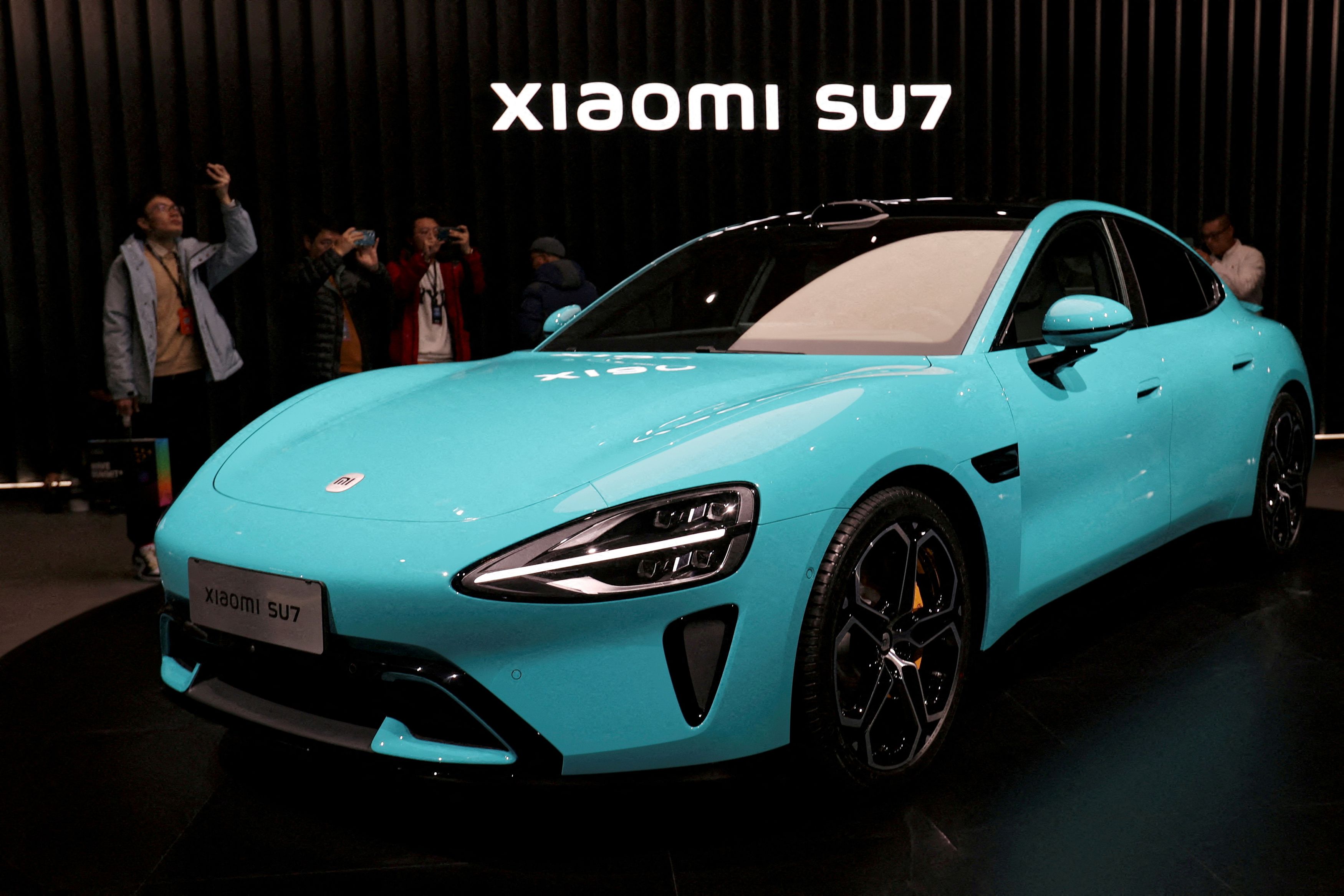 FILE PHOTO: Visitors film around Xiaomi's first electric vehicle, the SU7, displayed at an event in Beijing, China December 28, 2023. REUTERS/File Photo