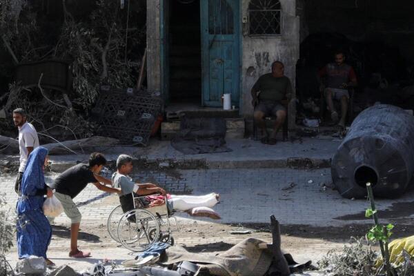 A young man pushes a wheelchair with an injured person, aftermath of Israeli strikes at the area, where Israeli hostages were rescued on Saturday, as Palestinian death toll rises to 274, amid the Israel-Hamas conflict, in Nuseirat refugee camp in the central Gaza Strip,