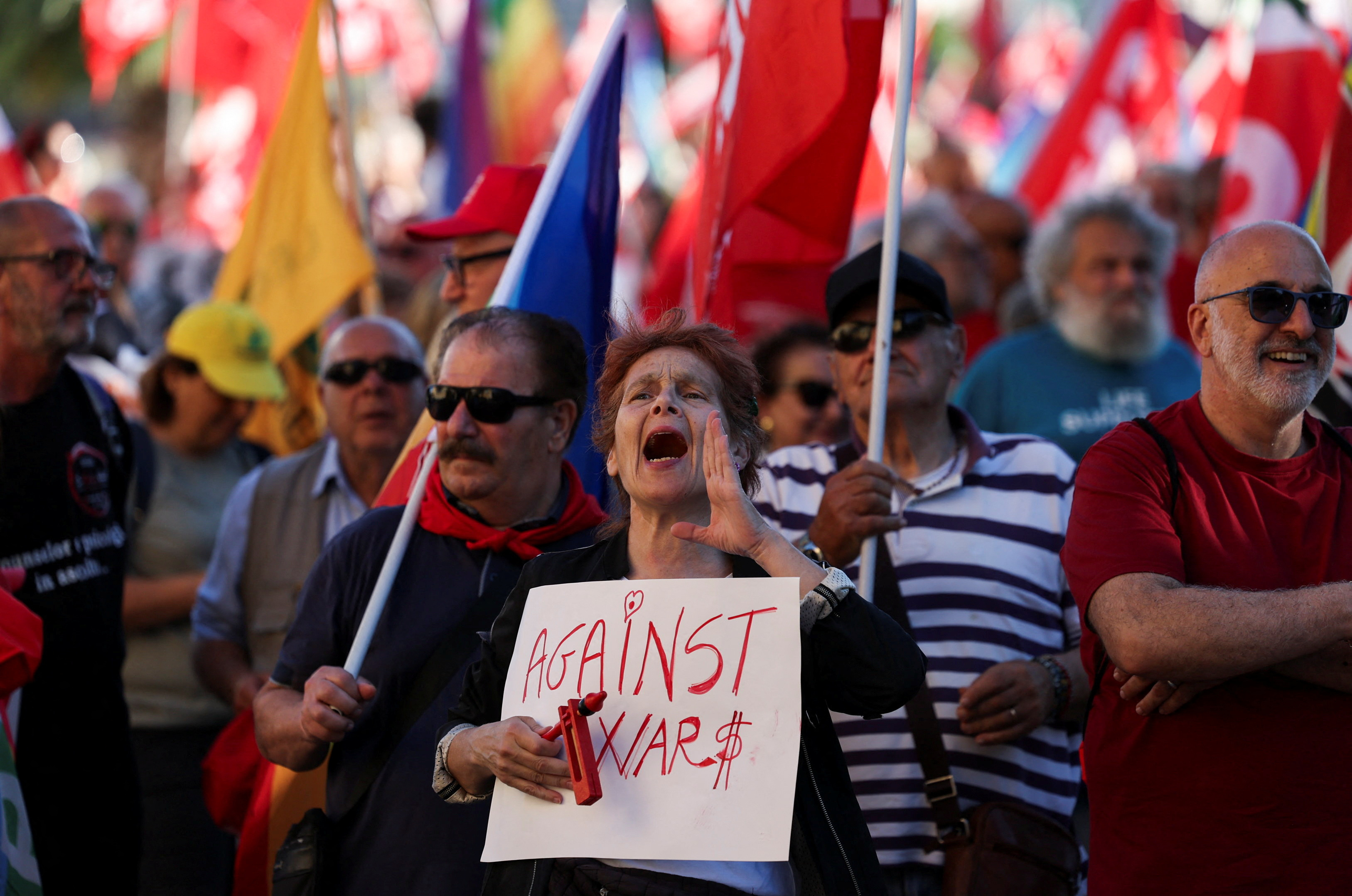A woman shouts as she holds a sign that reads "Against War$", during a protest against the ongoing G7 summit near Borgo Egnazia resort, the summit's venue, in Fasano, Italy, June 14, 2024.
