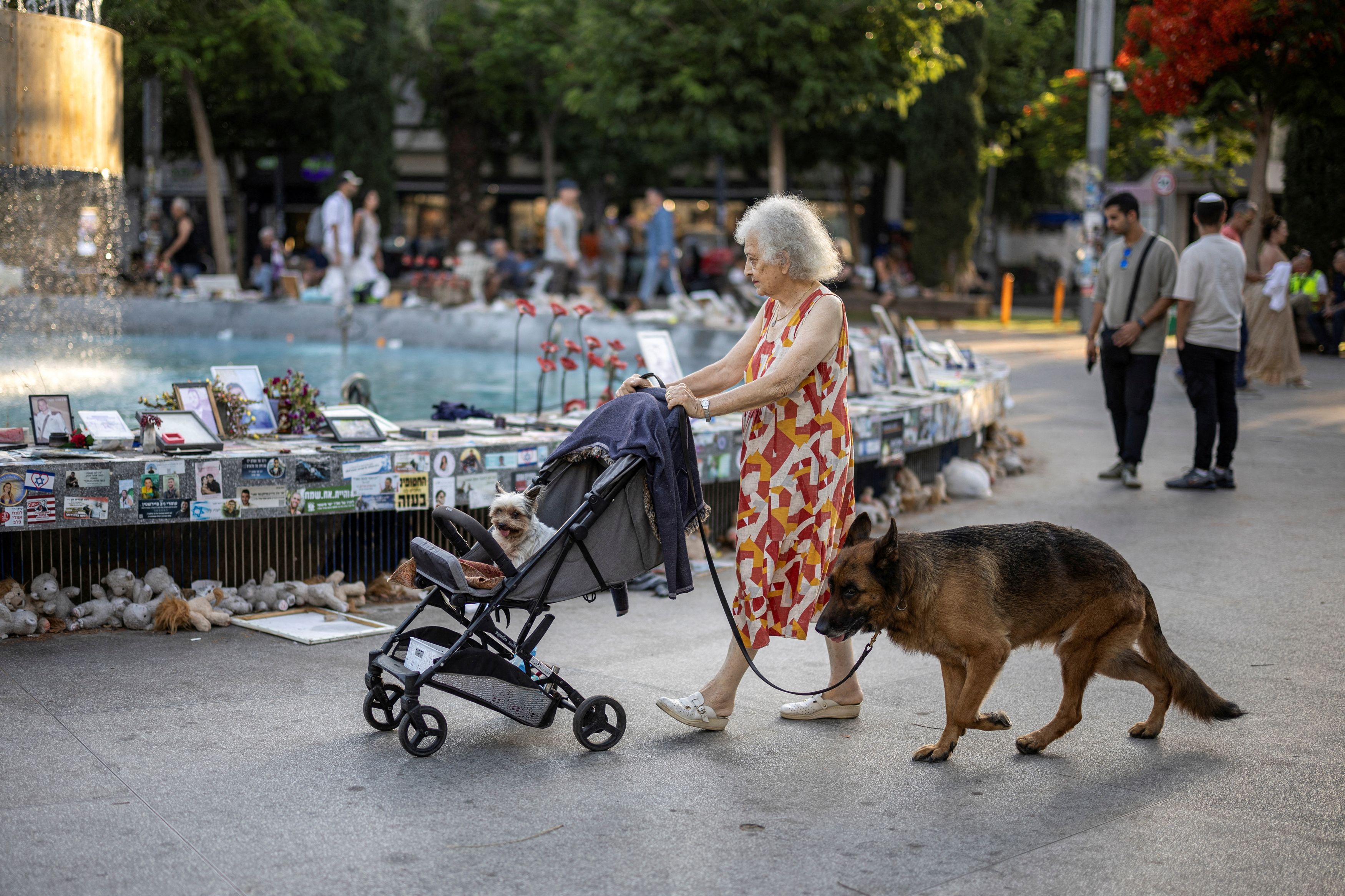 A woman walks past a fountain covered with memorabilia and pictures of hostages kidnapped during the deadly October 7 attack on Israel by Hamas, amid the ongoing Israel-Hamas conflict, at Dizengoff Square in Tel Aviv, Israel, June 13, 2024.