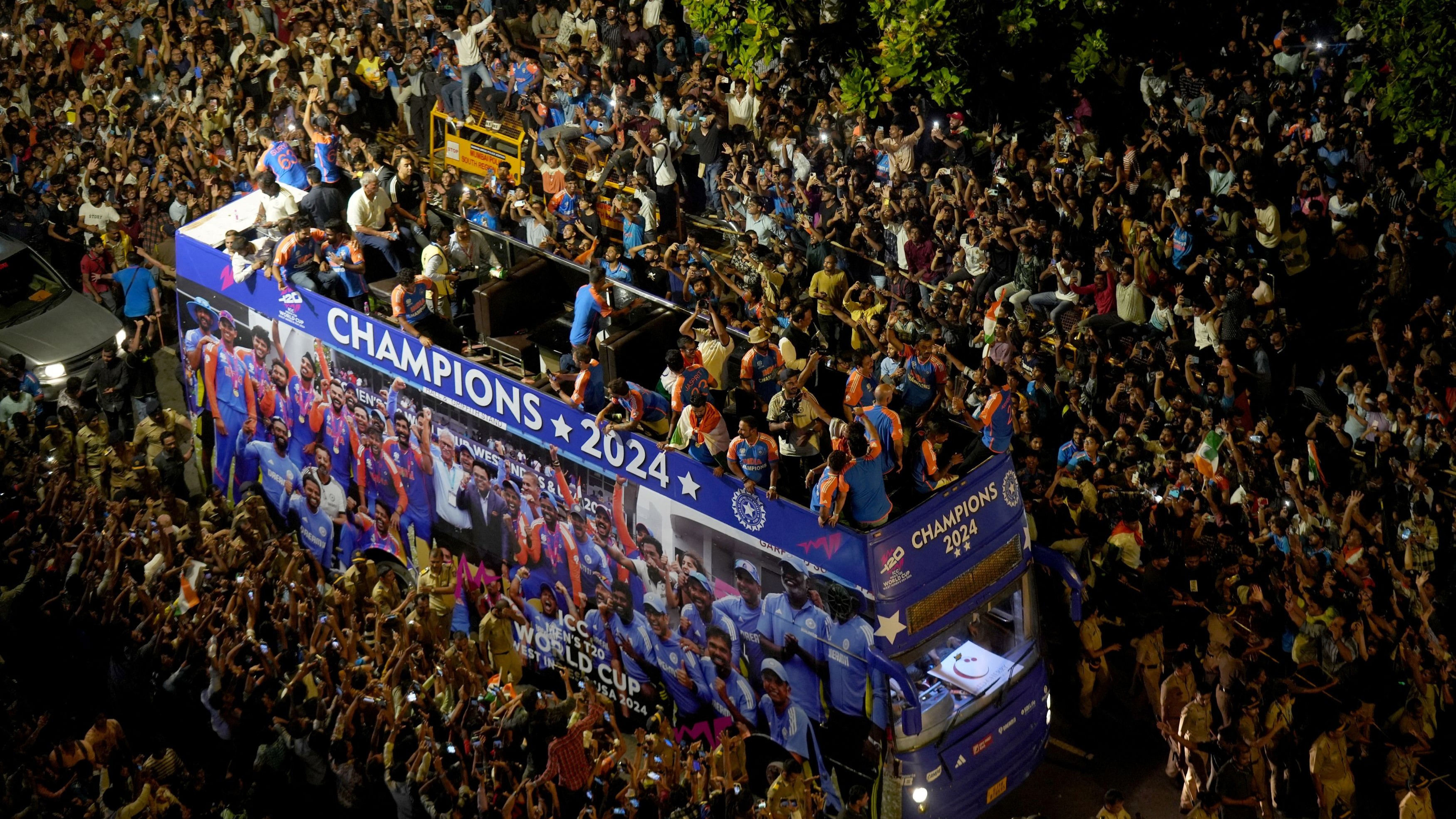 Fans crowd around a bus as Indian cricket team members take part in a parade to celebrate winning the ICC men's T20 World Cup, in Mumbai.