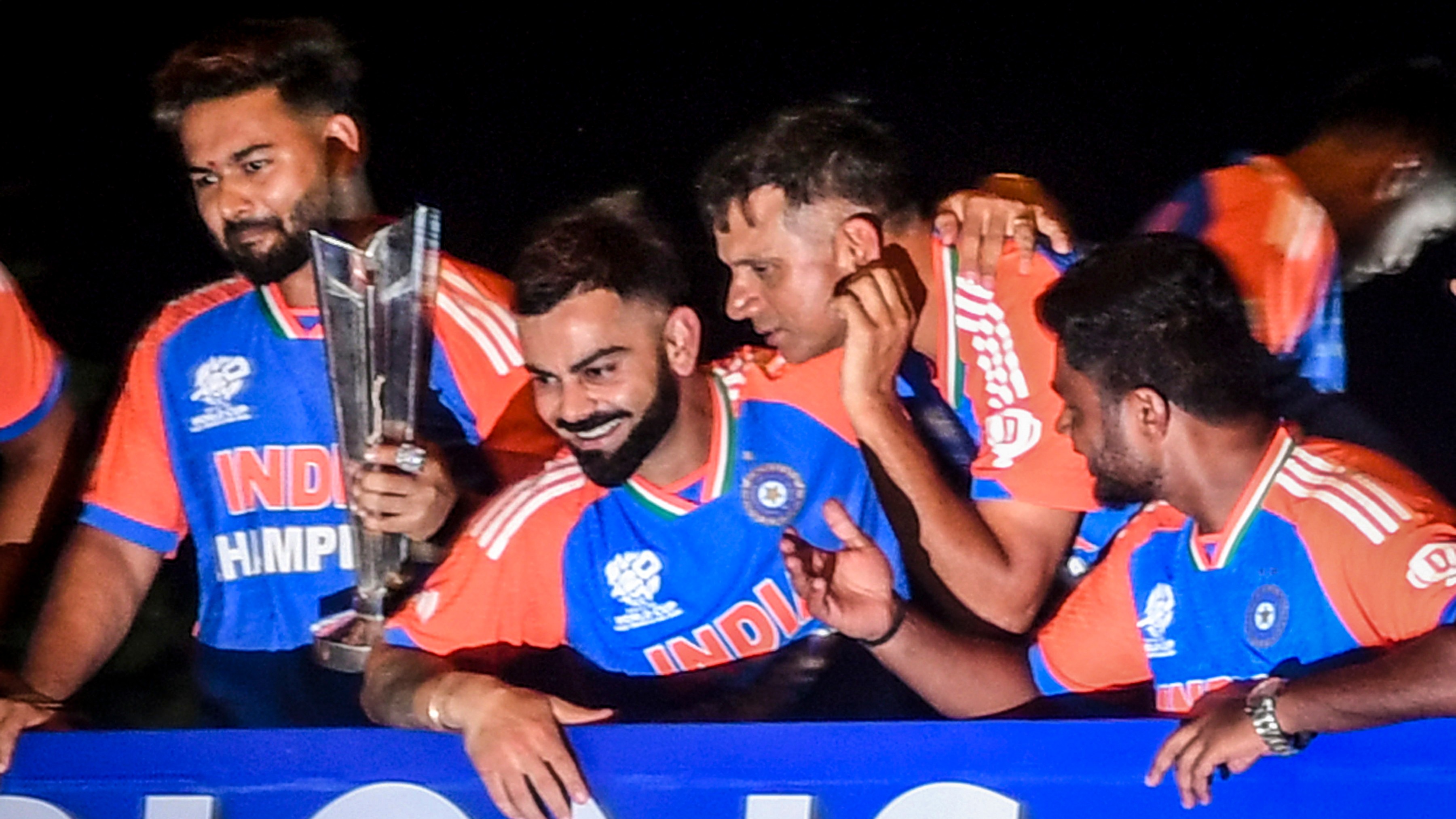 Players of the T20 World Cup-winning Indian cricket team with the championship trophy acknowledge fans during their open bus victory parade, in Mumbai.