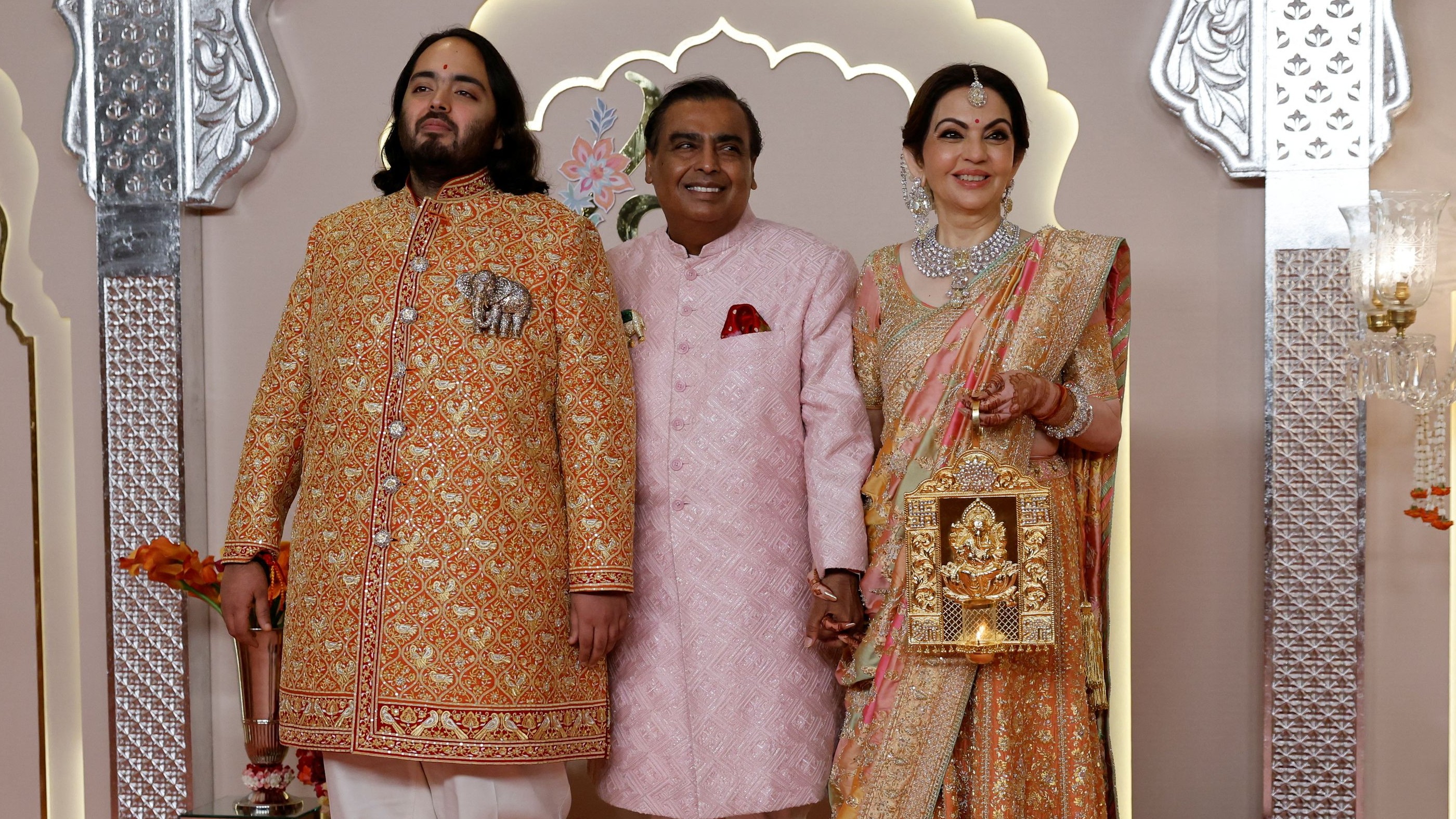 Anant, dressed in a rust orange sherwani, poses with his family on his arrival.
