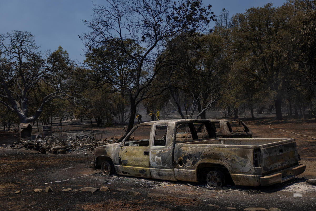 Firefighters work near burned vehicles after the Thompson fire affected a neighborhood near Oroville, California.