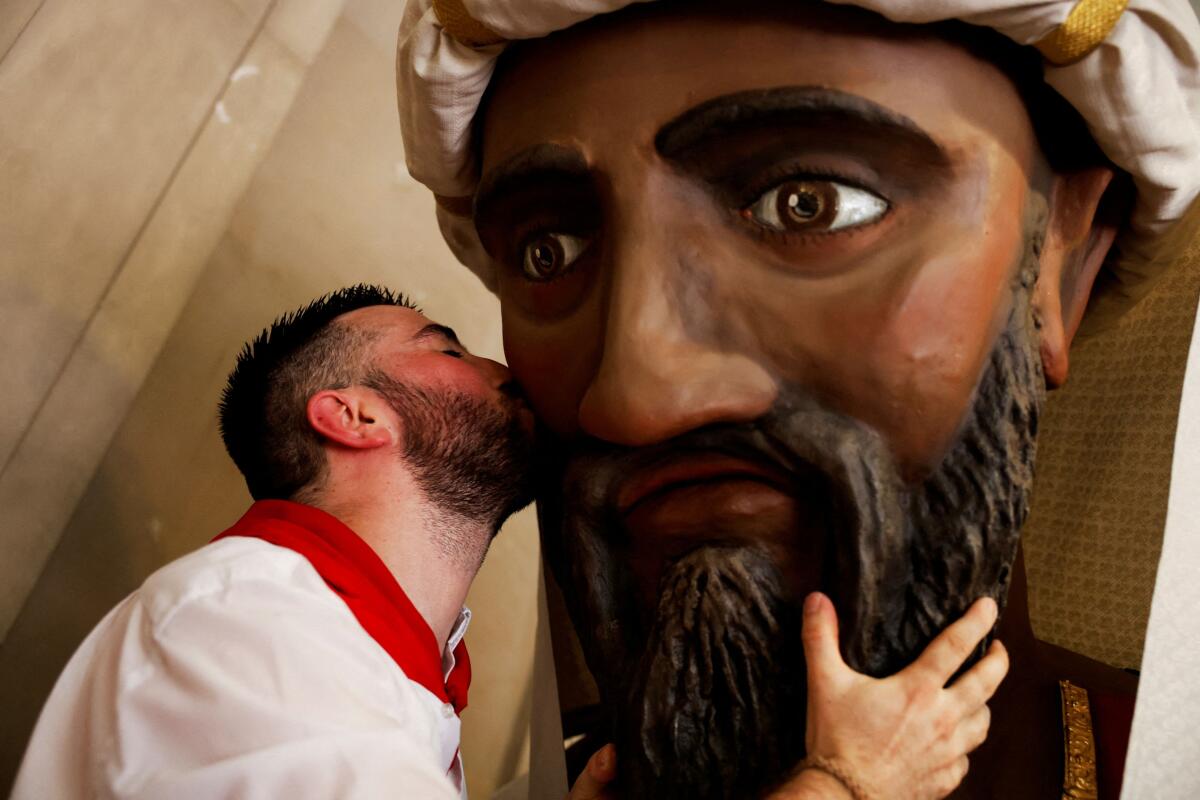 A member of San Fermin's "Comparsa de gigantes y cabezudos" (Parade of the giants and the big heads) kisses a giant's head during a farewell ceremony in Spain.