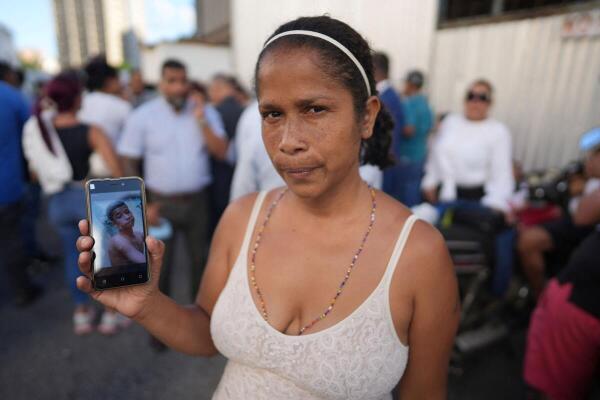 Lorena Malabe, 42, holds a phone with a picture of her 18 year old son Jeremy Malabe, detained during protests in Venezuela over the country's contested presidential election, outside a police headquarters, in Caracas, Venezuela.