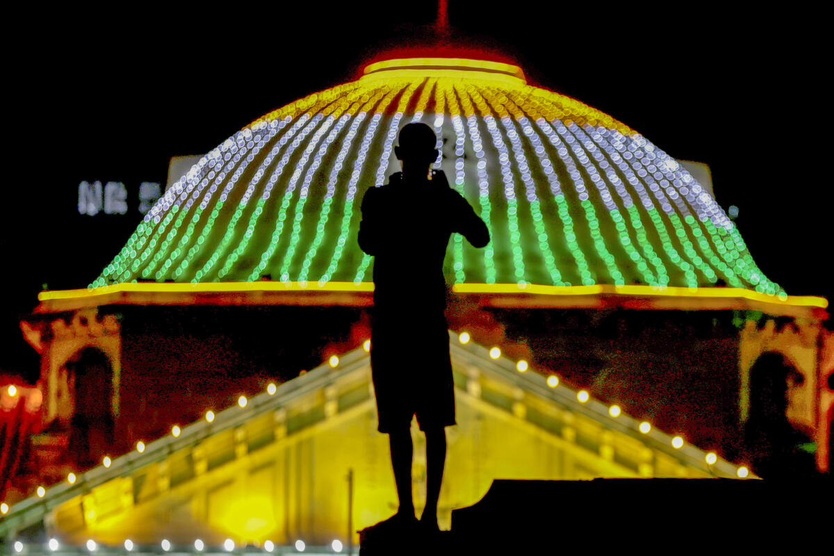 A man silhouetted against the illuminated Allahabad High Court building on the eve of the country's Independence Day, in Prayagraj.