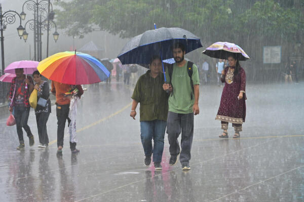 Pedestrains on a road amid heavy monsoon rain, in Shimla.