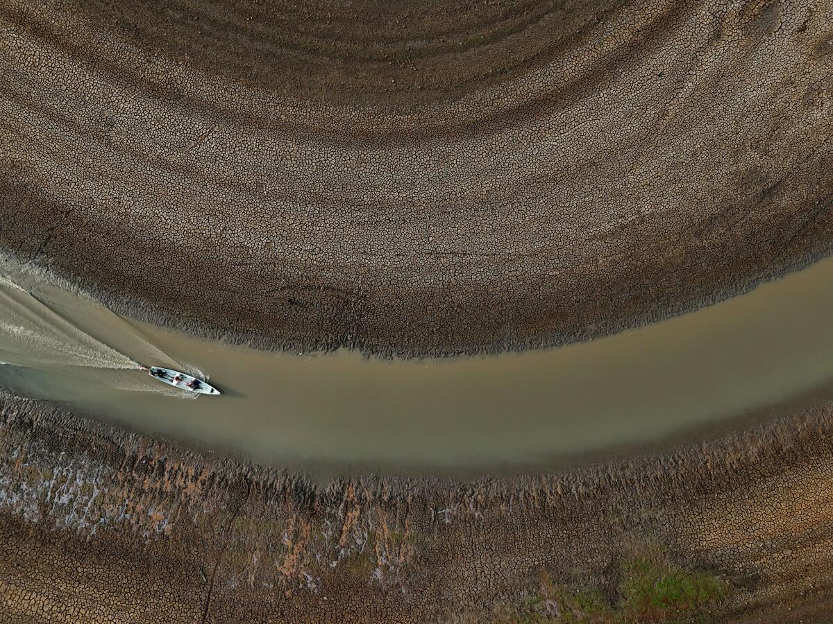 A drone view shows fishermen pushing an aluminium canoe to try to go fishing, in the middle of the dry bed of the Puraquequara lake caused by severe drought in the Amazon, in Manaus, Brazil