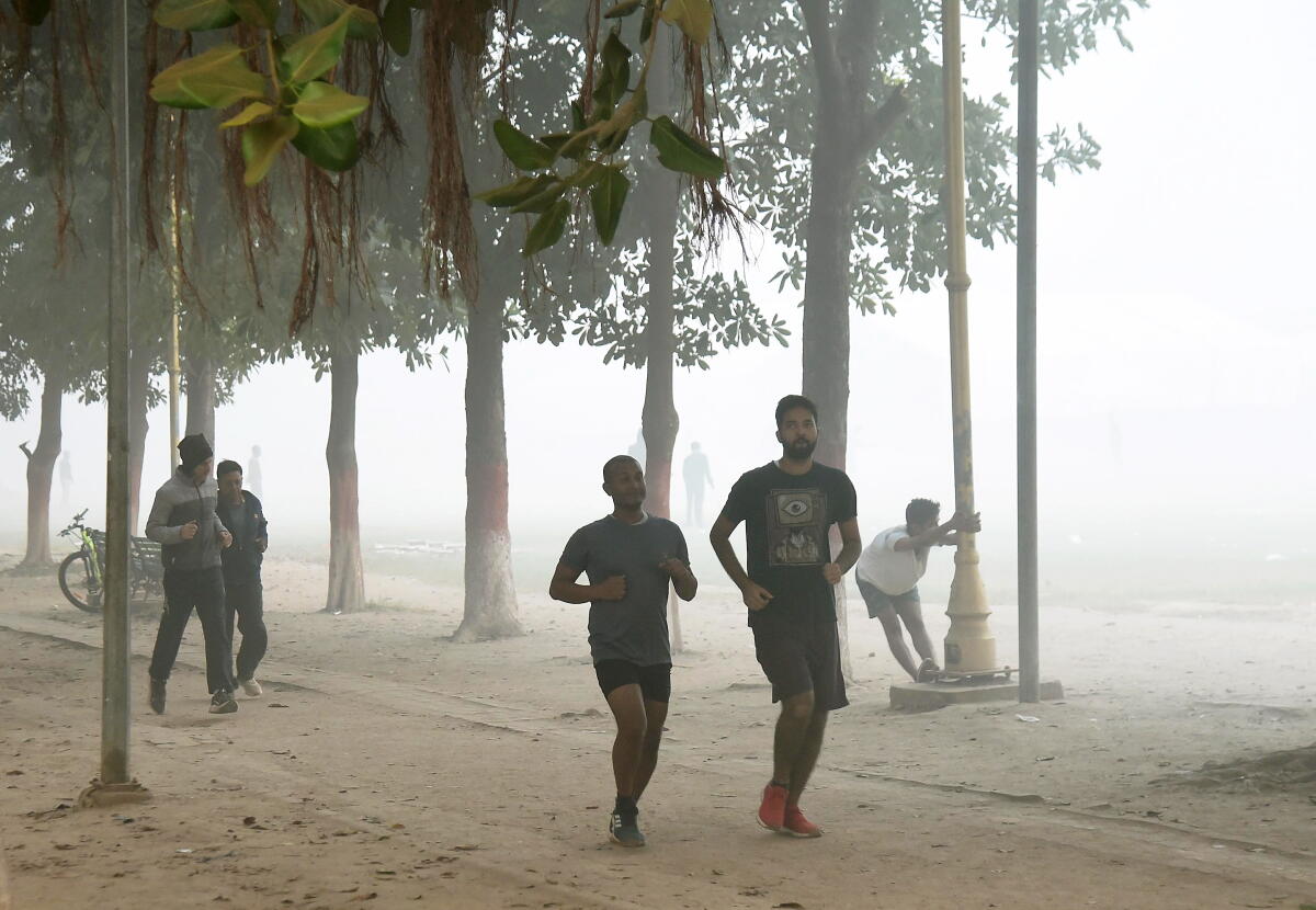 People take a morning walk at Gandhi Maidan on a cold winter morning amid smog, in Patna.