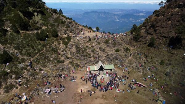 A drone view shows Catholic devotees gathering around the restored El Cristo de las Alturas (Christ of the Heights) statue at the shrine in the crater of Guatemala's Agua volcano in Santa Maria de Jesus, Guatemala
