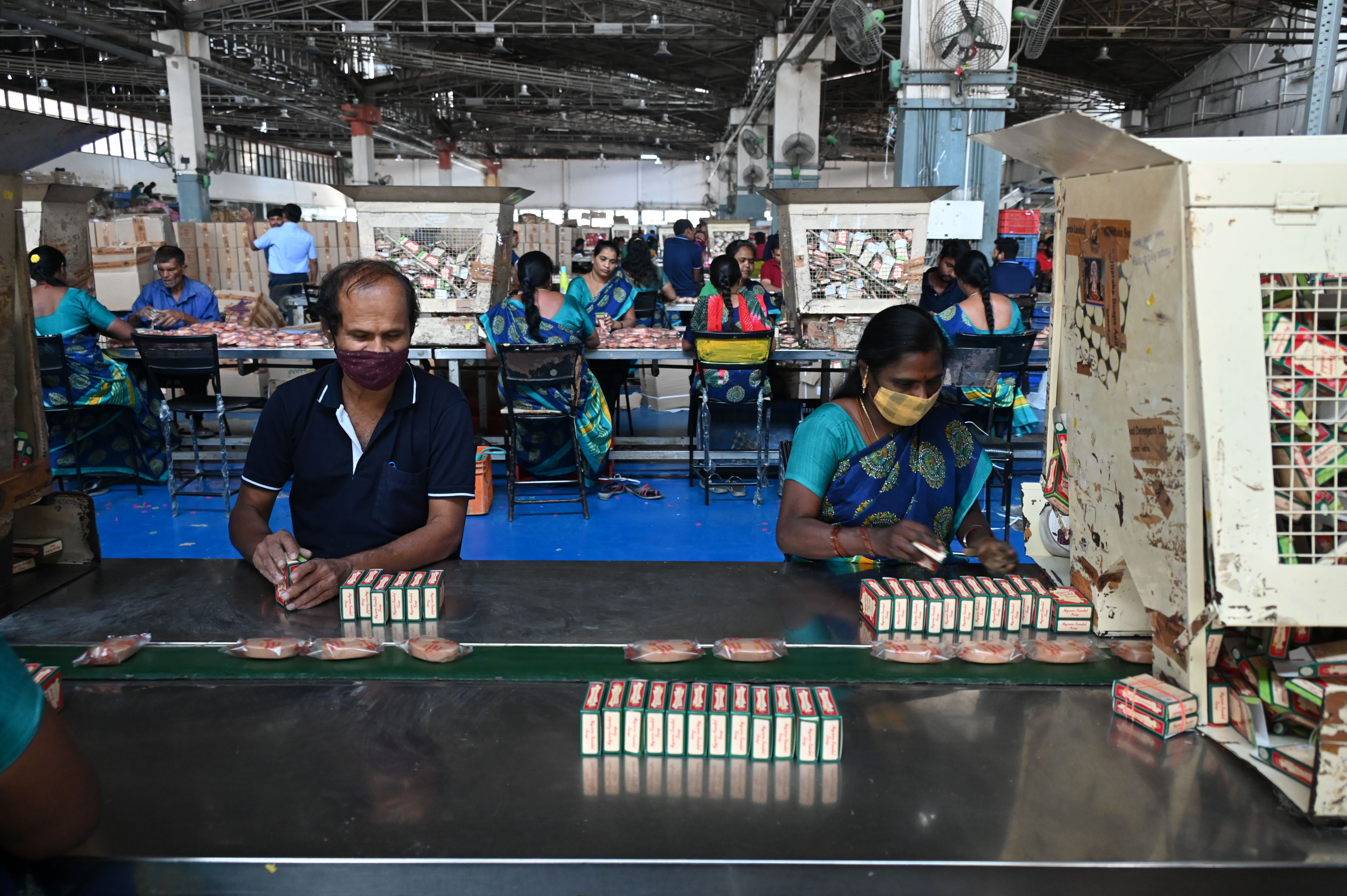 The staff pack the wrapped soap in the trademark red and green cardboard boxes