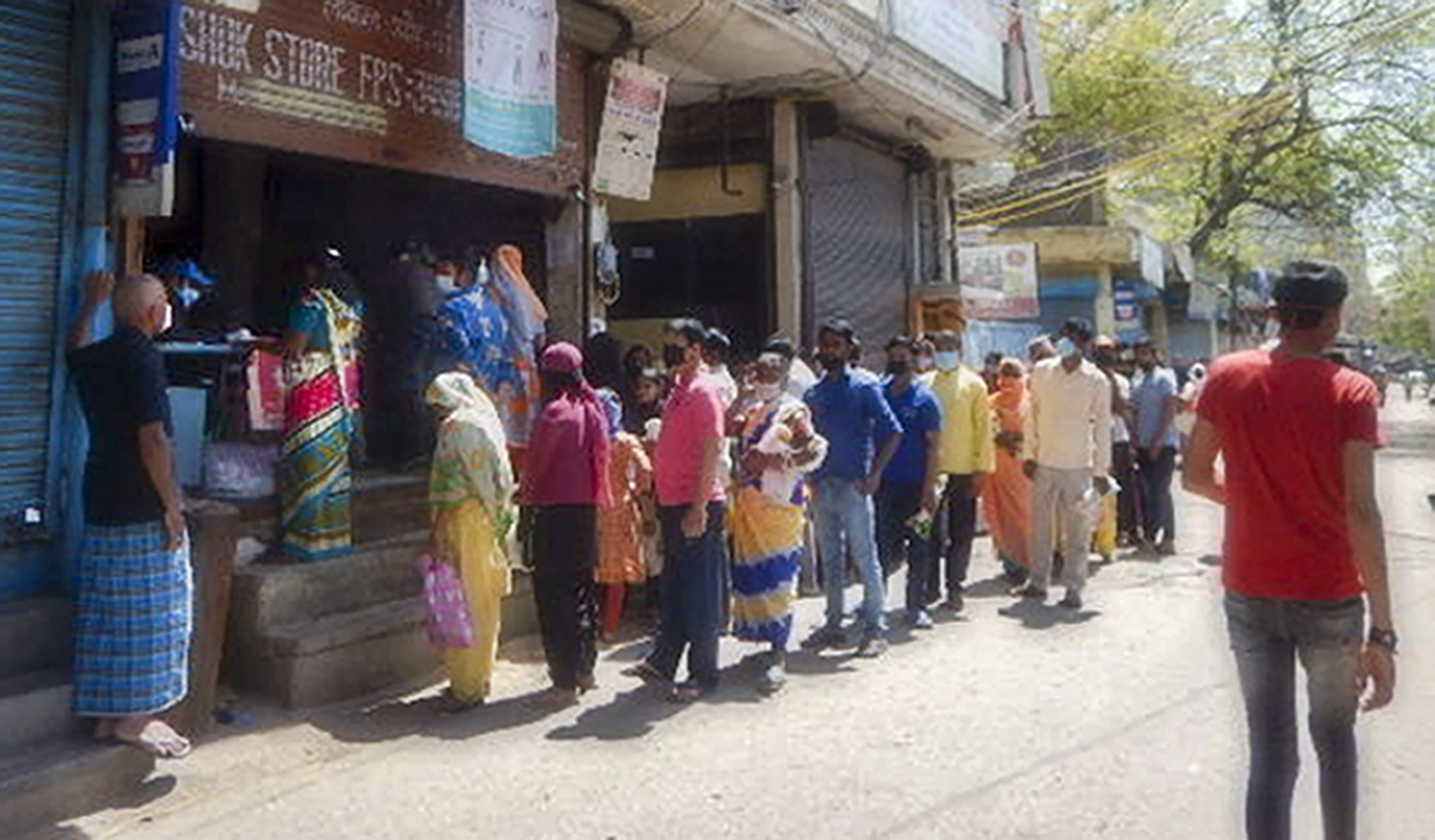 PDS beneficiaries stand in a queue before a ration depot in Delhi.