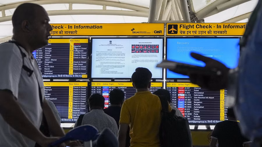 Passengers look at screens, one of them showing Blue Screen error, at T3 Terminal of the Indira Gandhi International Airport amid Microsoft outage, in New Delhi.