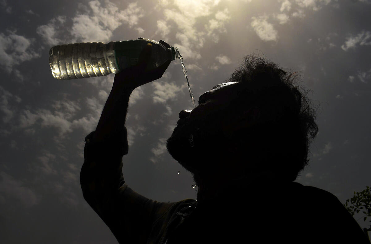 A man splashes water on his face on a hot summer day amid heatwave.