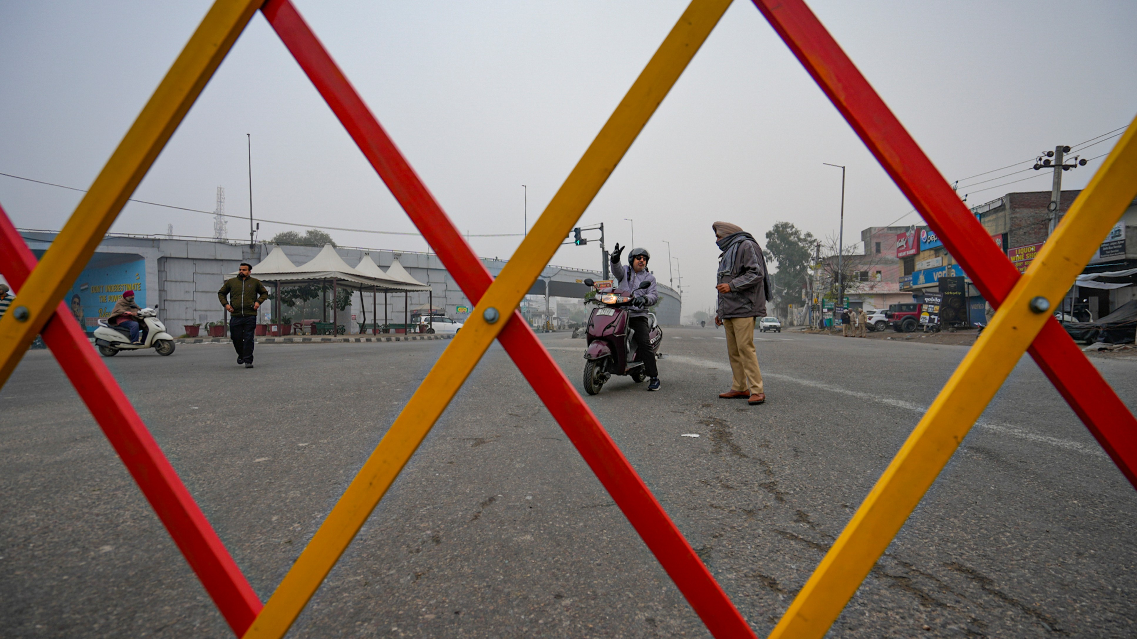 A commuter speaks with a policeman on a road blocked by farmers during the statewide 'bandh' called as part of their ongoing protest in Amritsar.