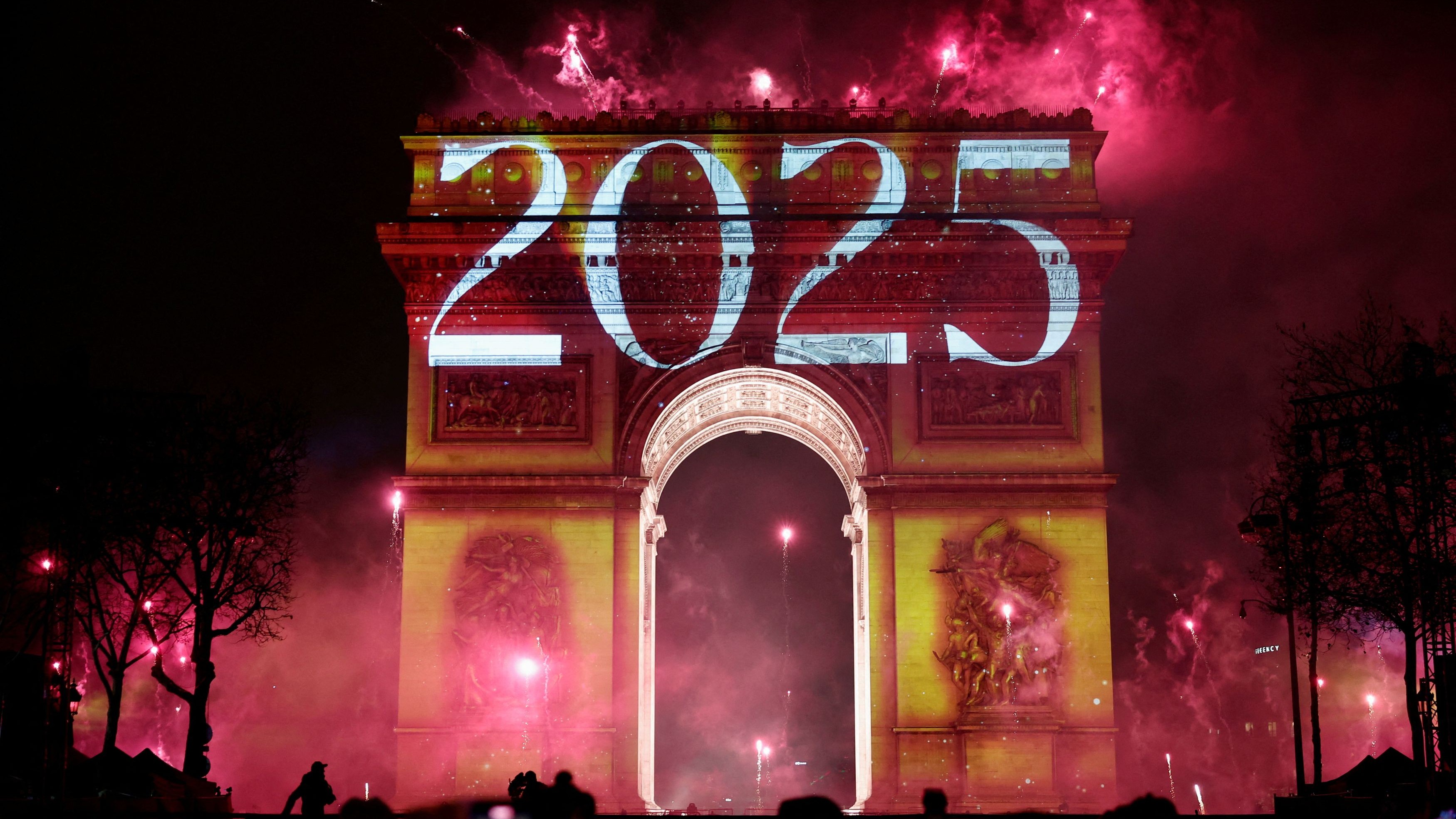 Fireworks explode as "2025" is projected onto the Arc de Triomphe during the New Year's celebrations on the Champs Elysees avenue in Paris, France.