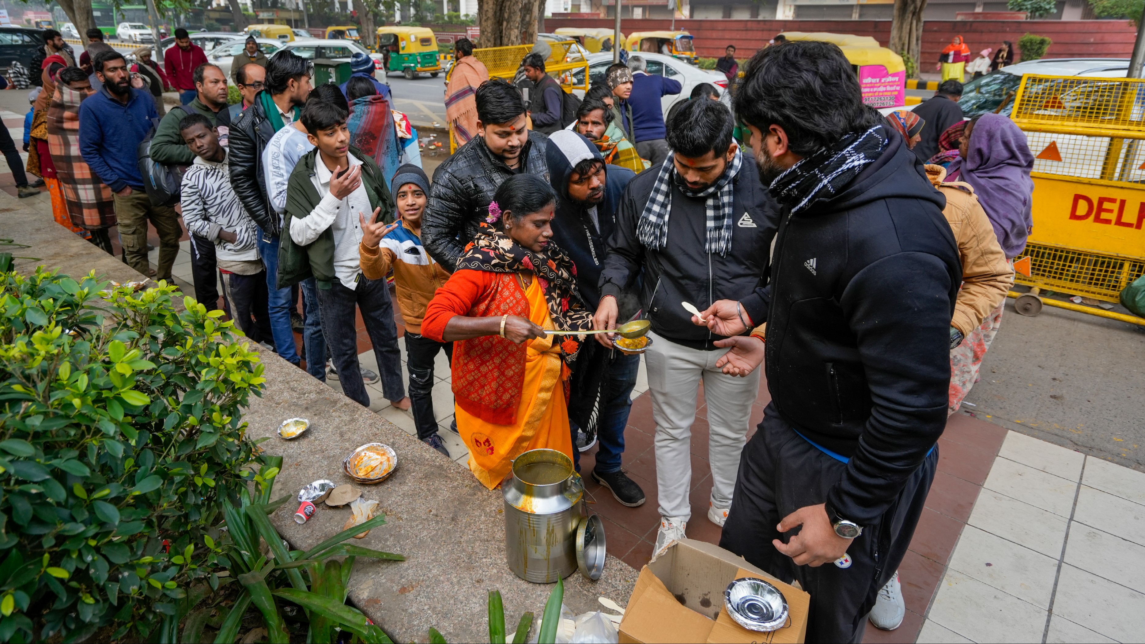 Devotees distribute food near Hanuman Mandir on the first day of the year 2025 in Delhi.