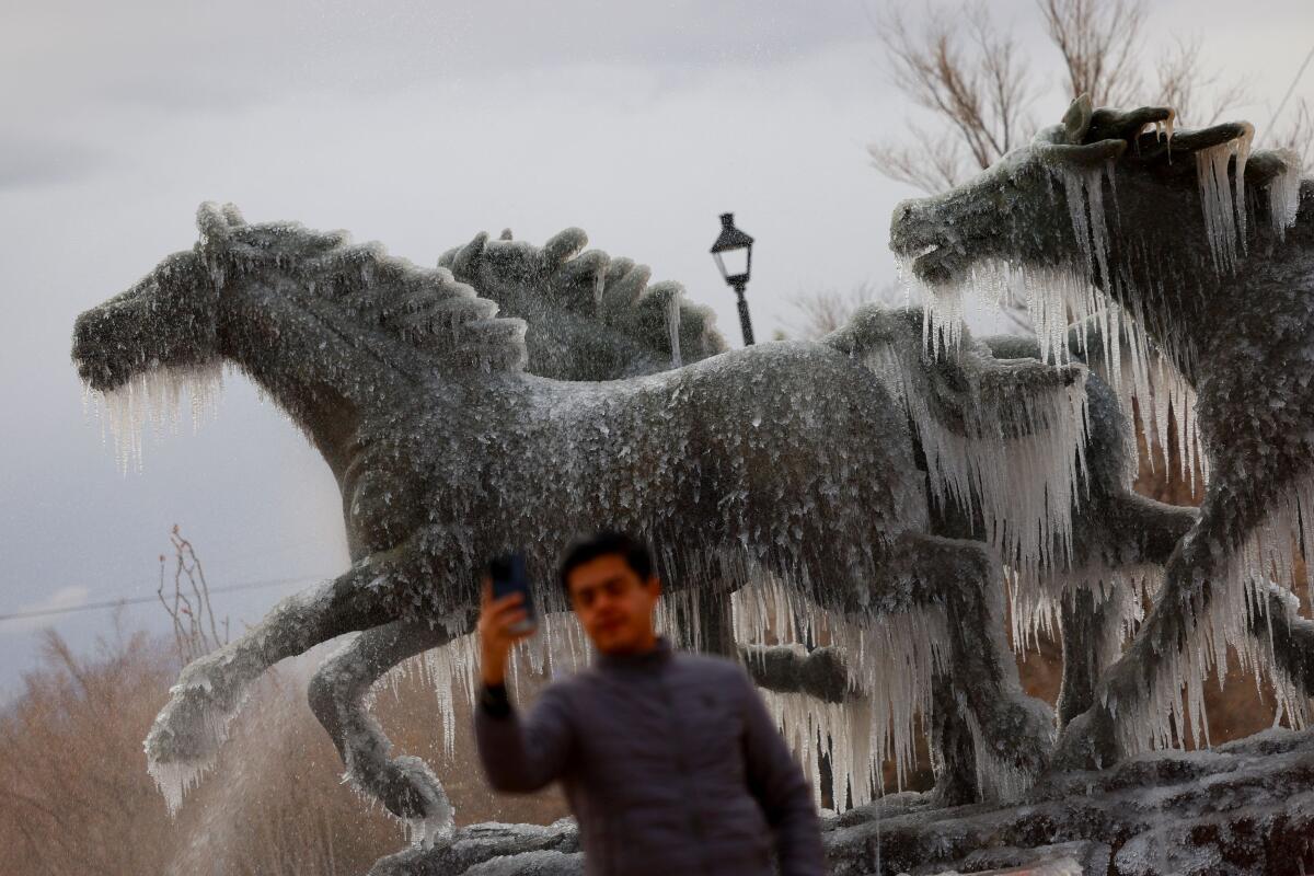 A man takes a selfie at the "Los Indomables" monument with frozen water during a day of low temperatures, in Ciudad Juarez, Mexico January 8, 2025.