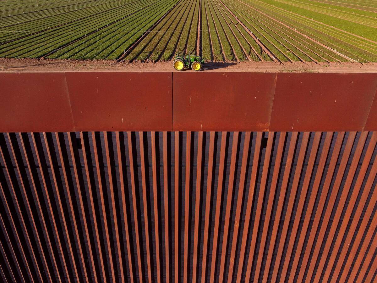 A drone view shows a tractor at a field in Calexico, California, US, behind the wall on the US-Mexico border, as seen from Mexicali, Mexico.