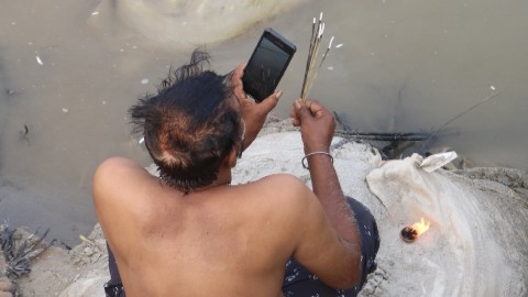A devotee video-calling while offering a prayer near a bridge at the Sangam Snan Ghat at the MahaKumbh 2025 at Prayagraj, Uttar Pradesh.