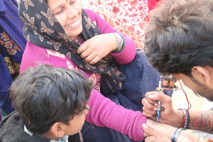 A devotee gets a religious insignia tattooed on her forearm, at the MahaKumbh 2025, at Prayagraj, Uttar Pradesh, January 13