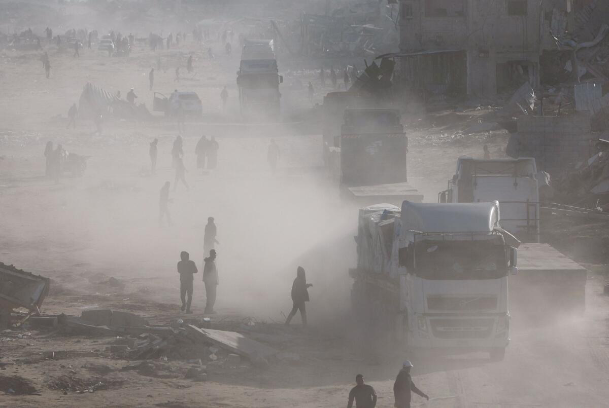 Palestinians rush to take aid from moving trucks entering Rafah, following a ceasefire between Israel and Hamas, in the southern Gaza Strip, January 20, 2025.
