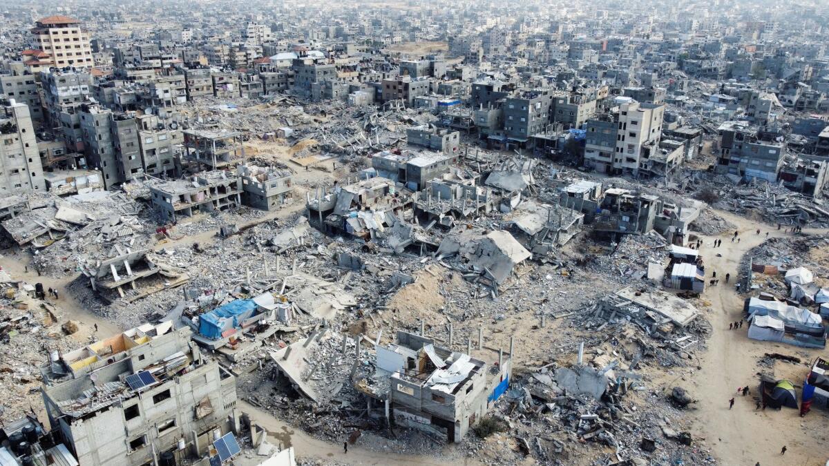 A drone view shows Palestinians walking past the rubble of houses and buildings destroyed in Israeli strikes during the war, following a ceasefire between Israel and Hamas, in Khan Younis in the southern Gaza Strip, January 20, 2025.