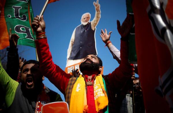 With cutout of PM Modi in the background, BJP supporters celebrate the saffron party's performance in the national capital.