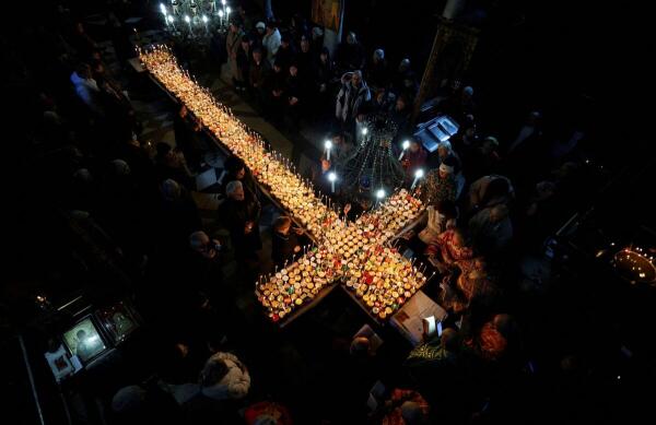 Worshippers gather around candles stuck to jars with honey during a religious service to mark the day of Saint Haralampi, the Orthodox patron saint of beekeepers, in the church of the Presentation of the Blessed Virgin in Blagoevgrad, Bulgaria