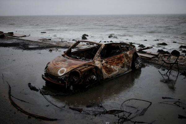 A vehicle burnt by the wildfires sits under a rain storm in the Pacific Palisades burn zone, in Los Angeles, California, U.S., February 13, 2025.