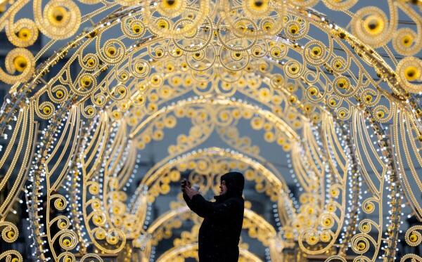 A man takes photos via his smartphone while standing next to street decorations in Moscow, Russia, February 13, 2025.