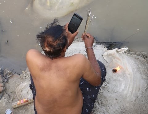 A devotee video-calling while offering a prayer near a pontoon bridge at the Sangam Snan Ghat at the MahaKumbh 2025, at Prayagraj, Uttar Pradesh, January 13.