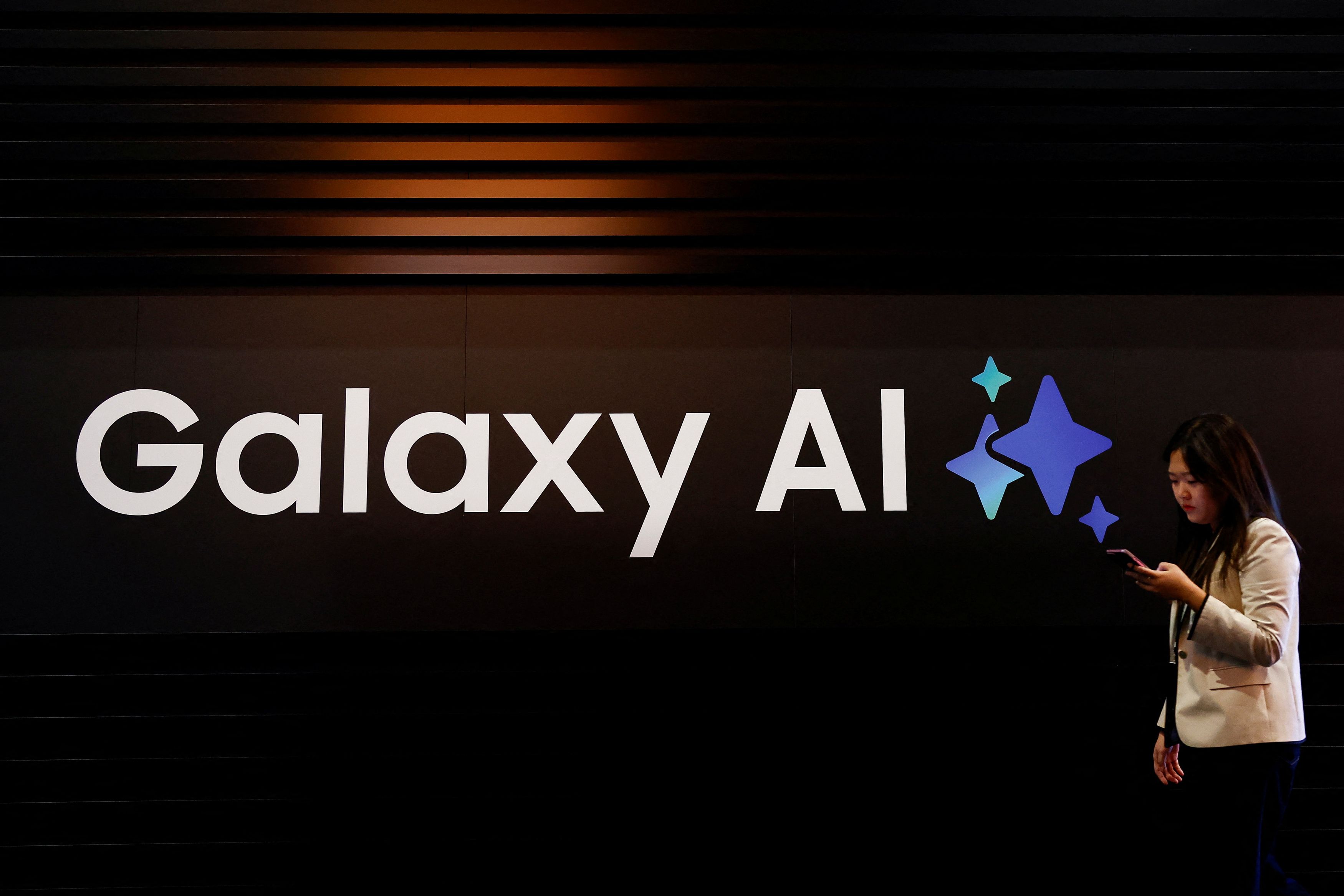 A woman walks past a Galaxy AI sign during the 2025 Mobile World Congress  in Barcelona, Spain.