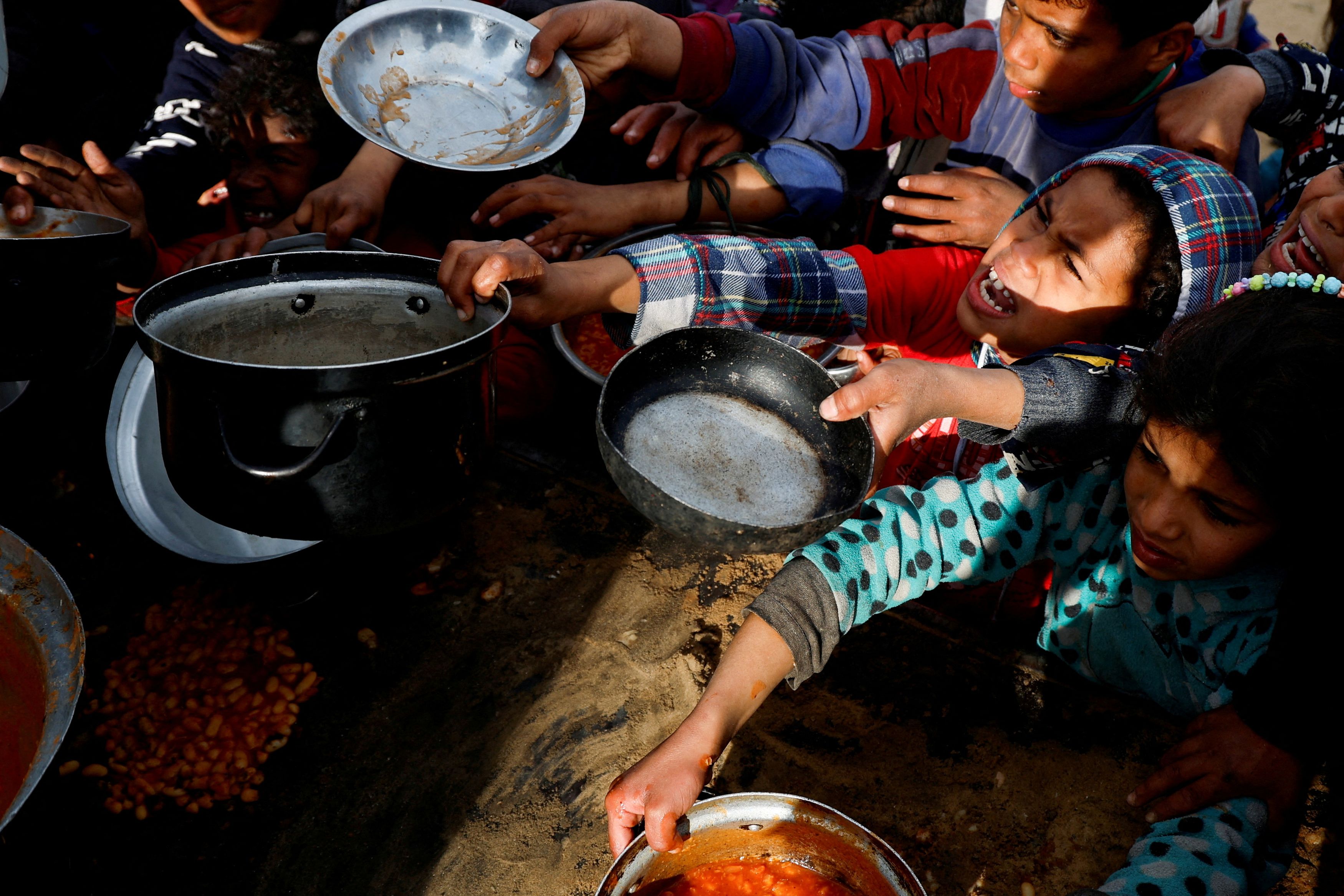 Palestinian children gather to receive food cooked by a charity kitchen, during the Muslim holy month of Ramadan, in Khan Younis, in the southern Gaza Strip, March 3, 2025.