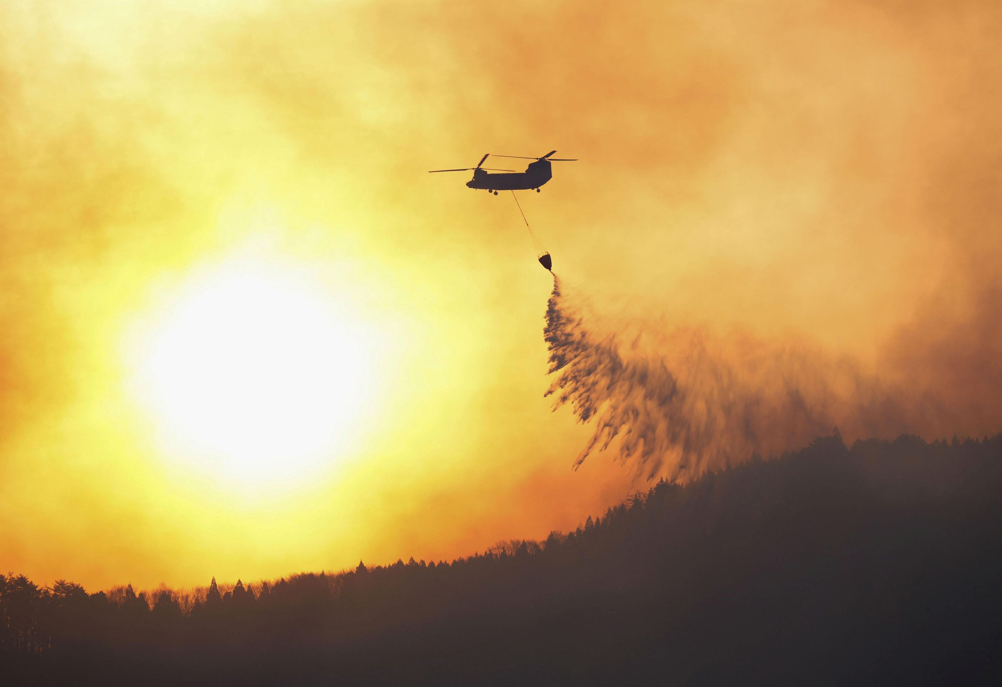 A Japanese Self-Defense Force helicopter conducts firefighting operations from the air on a wildfire site in Ofunato, Iwate Prefecture, northeastern Japan, March 4, 2025, in this photo taken by Kyodo.